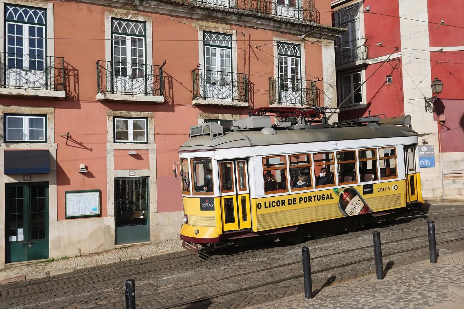 un tramway jaune traditionnel longe les façades colorées d'une rue de Lisbonne