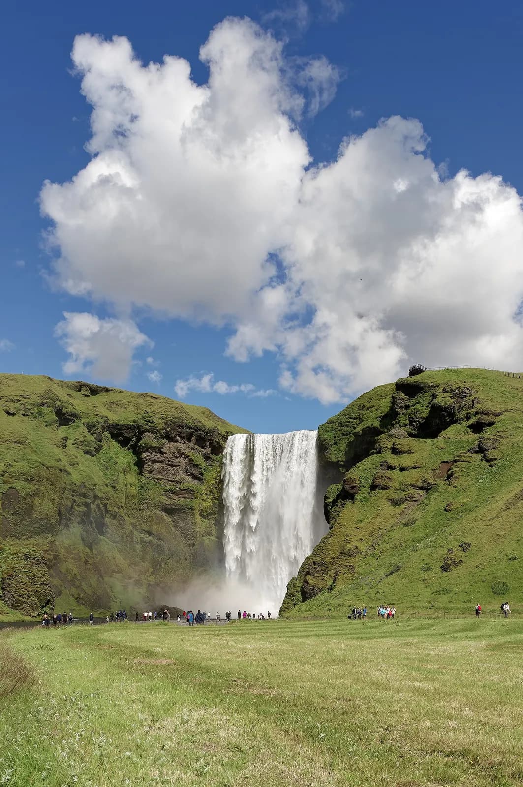 la cascade de Skógafoss tombe entre deux falaises verdoyantes dans le sud de l'Islande