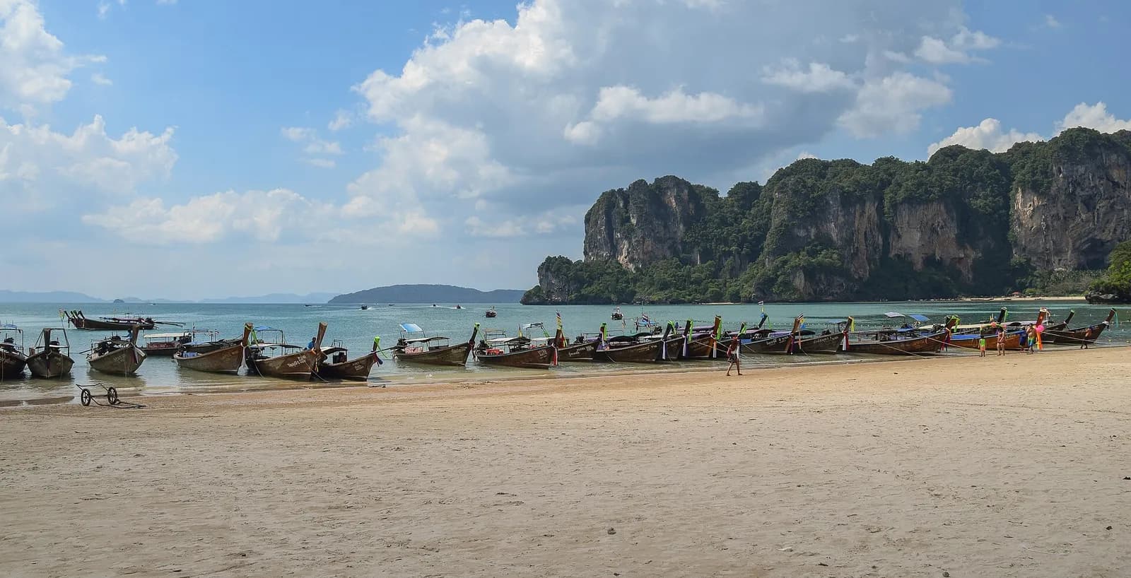 des bateaux à longue queue alignés sur la plage de Railay face aux falaises calcaires de Krabi