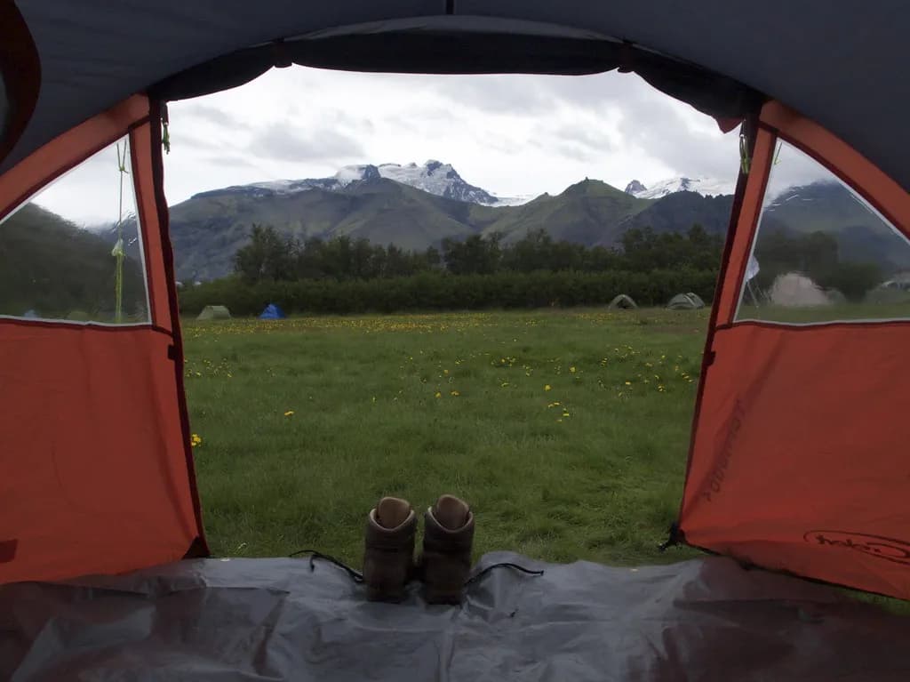 vue sur les montagnes de Skaftafell depuis l'entrée d'une tente, chaussures de randonnée au premier plan