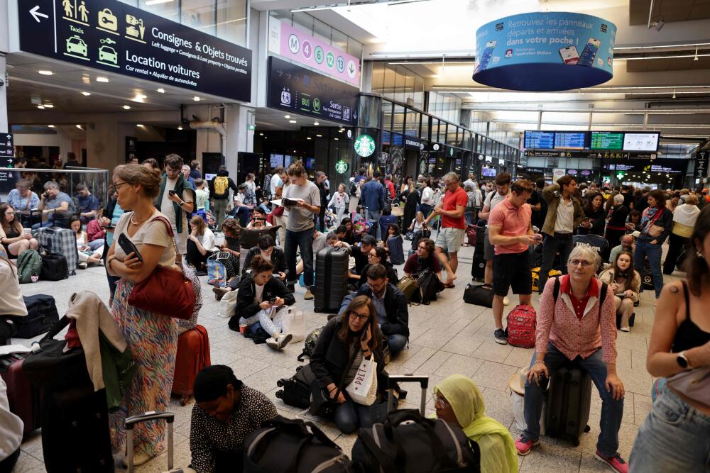 Passengers wait for their train departures at the Gare Montparnasse train station in Paris on July 26, 2024 as France's high-speed rail network was hit by malicious acts disrupting the transport system hours before the opening ceremony of the Paris 2024 Olympic Games. According to SNCF a massive attack on a large scale hit the TGV network and many routes will have to be cancelled. SNCF urged passengers to postpone their trips and stay away from train stations. (Photo by Thibaud MORITZ / AFP)