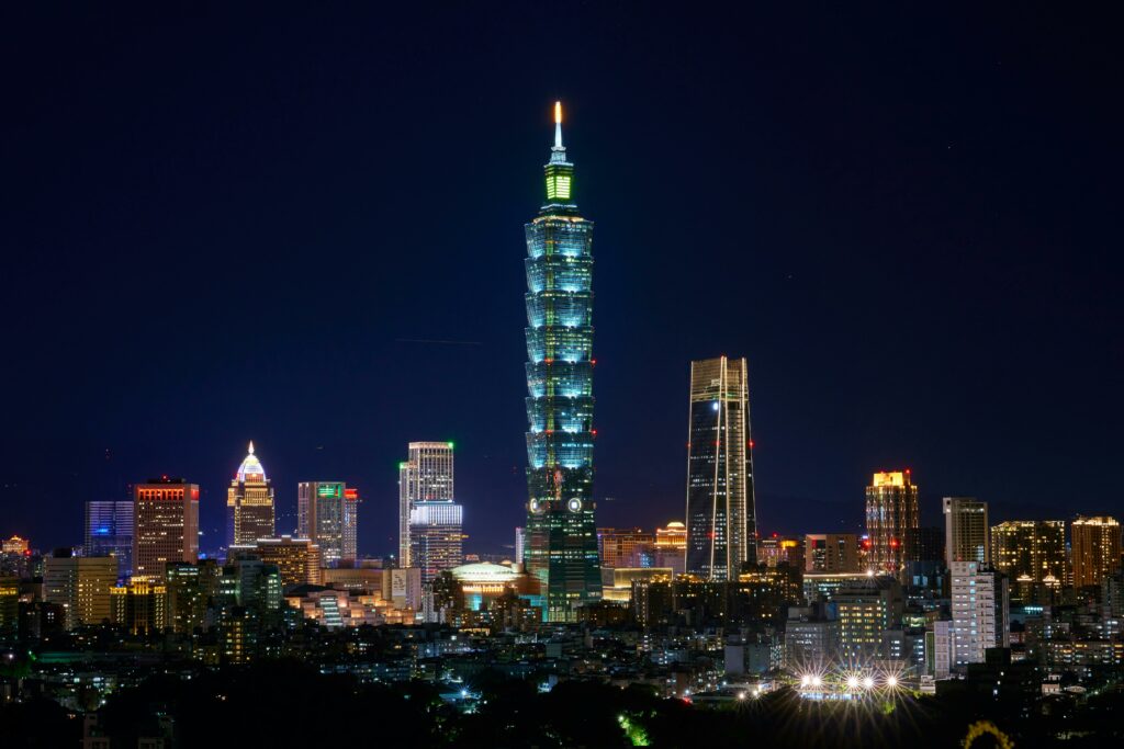 Illuminated Taipei 101 and city skyline at night showcasing modern urban architecture.